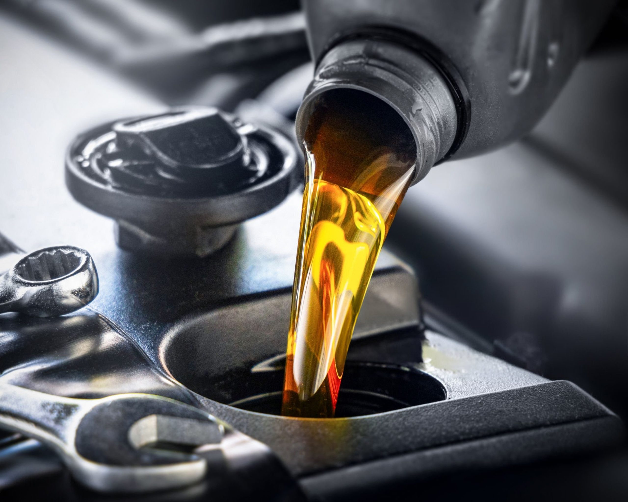 After changing the oil, a mechanic pours in the fresh engine oil into the car.